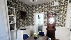 Un espace repas comprenant une table, des chaises, un lustre et une horloge.