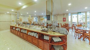 A spacious buffet area with a long counter, various food and drink stations, and a seating area with wooden chairs and tables. - Sunrise Hotel Da Lat (Xuan Huong - Da Lat)