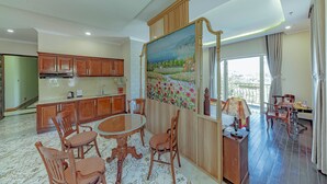 A spacious living room with a dining area, wooden cabinets, and a large painting on the wall. - Sunrise Hotel Da Lat (Xuan Huong - Da Lat)