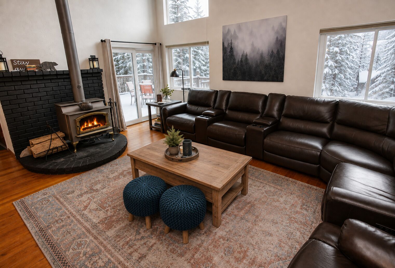 Una sala de estar acogedora con chimenea, sofá de cuero y un amplio ventanal con vista nevada.