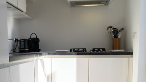 A modern kitchen with white cabinetry, a black countertop, and a built-in stove. - Seagull. (Egmond aan Zee)