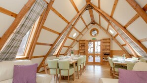 A cozy, triangular-roofed dining area with wooden beams, light-colored leather sofas, and a central table set for dining. - Beautiful private villa for 16 guests with WIFI, TV, patio, pets allowed and panoramic view (Ayr)