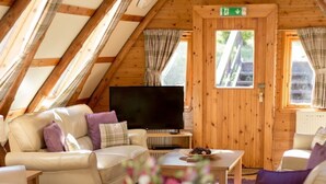 A cozy room with a wooden ceiling, a sofa, a TV, and a dining table set for two. - Beautiful private villa for 16 guests with WIFI, TV, patio, pets allowed and panoramic view (Ayr)