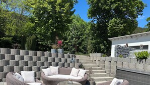 Un espace patio aménagé avec des meubles en osier et un mur en pierre.