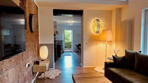 Un salon moderne avec un mur en briques, une table basse en bois, un canapé, une lampe et un téléviseur fixé au mur.
