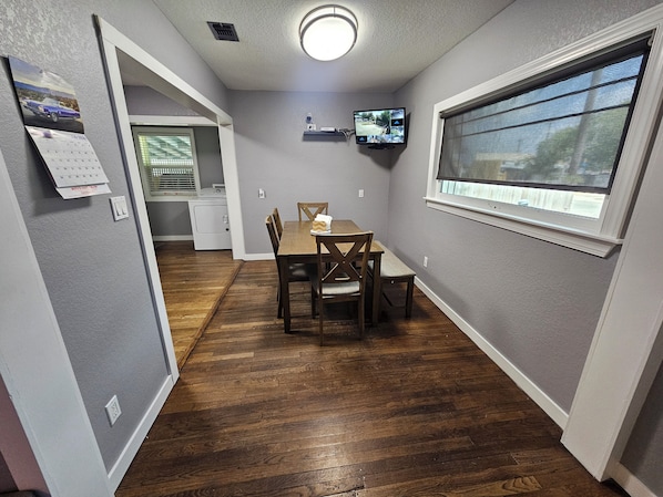 A compact kitchen with a dining area, a washing machine, and a security camera.