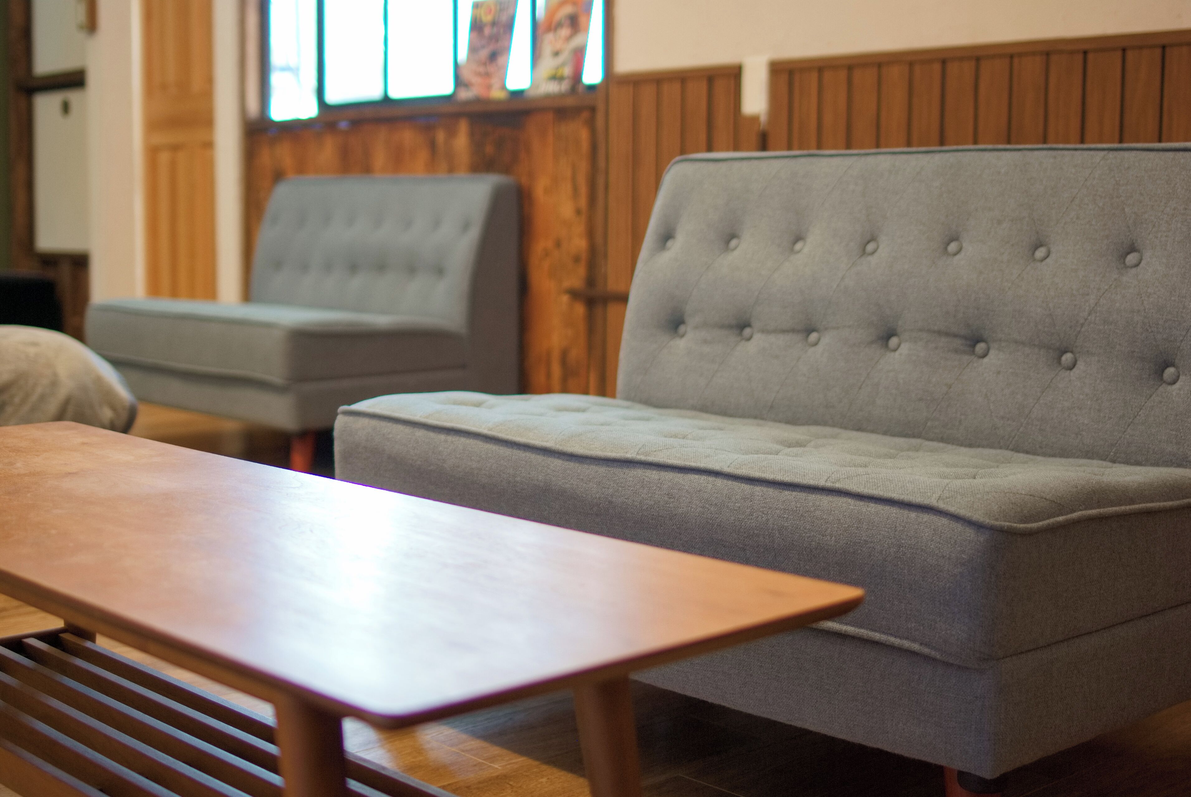 A room with a grey sofa, a wooden table, and a wooden bench.