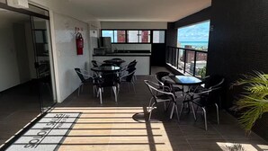 An outdoor patio area with a yellow ceiling, black and white tiled flooring, and a view of the cityscape. - FLAT VIP SOLON MANAIRA (João Pessoa)