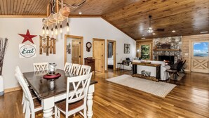 A spacious dining area with a wooden ceiling, a chandelier, and a star decoration on the wall. - Gateway Getaway (Old Fort)