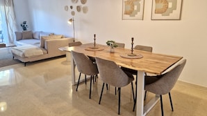 Un espace de salle à manger moderne avec une table en bois, des chaises à revêtement gris et des luminaires suspendus.