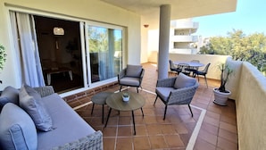 Un balcon avec un canapé, des chaises, une table et une plante en pot.