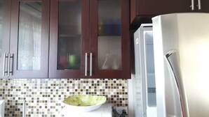 Une cuisine avec des meubles en bois foncé, un réfrigérateur en acier inoxydable et un dosseret carrelé.