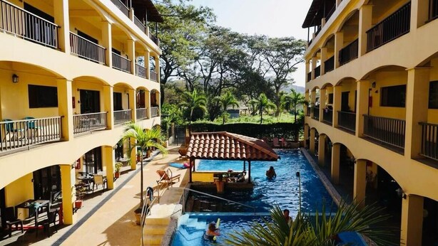Un hôtel doté de nombreux balcons, d’une piscine centrale et d’espaces de détente en plein air.