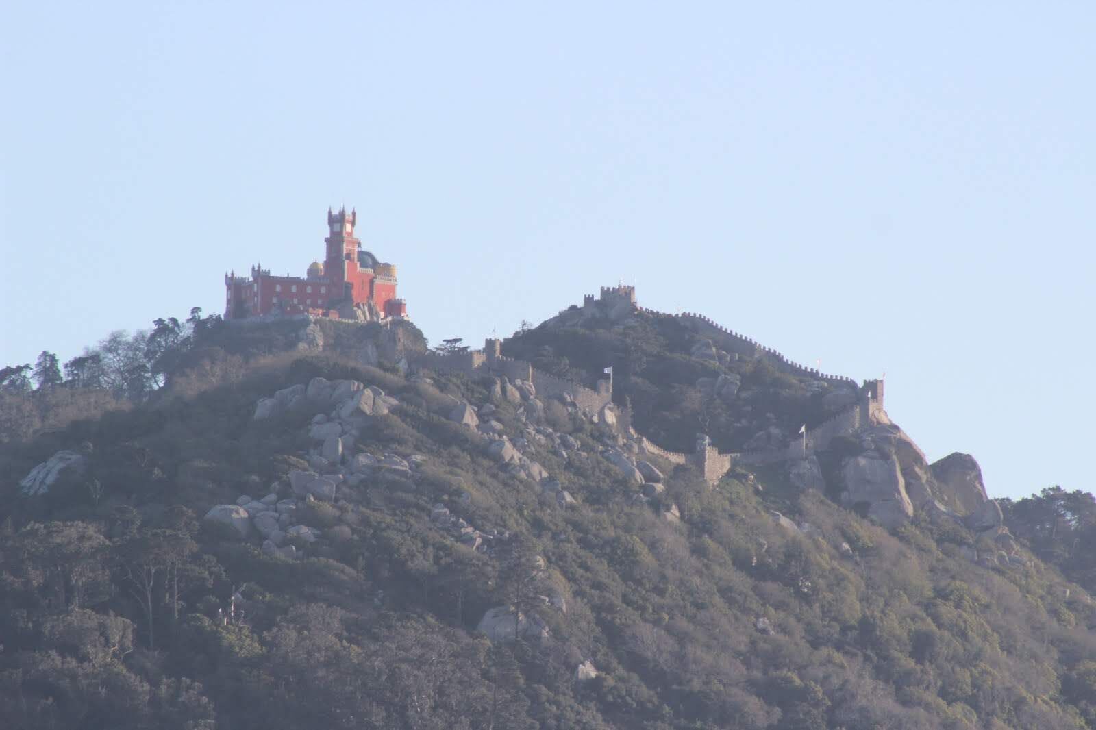 A castle-like structure on a hill with rocky terrain and sparse vegetation.