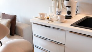Une cuisine moderne avec un plan de travail blanc, une machine à café et un vase rempli de fleurs.