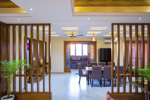 A spacious dining area with a high ceiling, recessed lighting, and a view into the kitchen. - Alaya Stays BYDM The Sky Heaven - 4 BHK Penthouse 15 Min from Triveni Ghat With Balcony & Lift (Rishikesh)