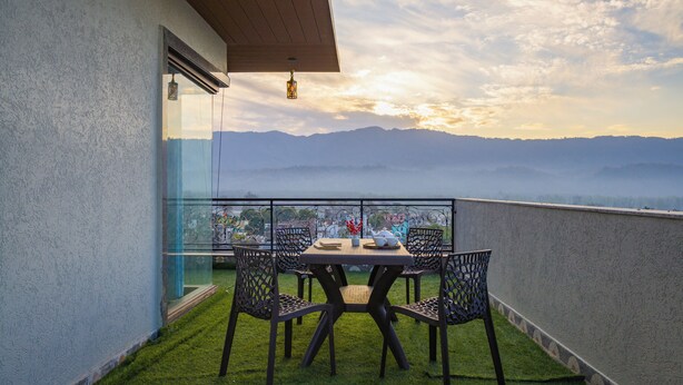 A balcony with a table and chairs, overlooking a mountainous landscape. - Alaya Stays BYDM The Sky Heaven - 4 BHK Penthouse 15 Min from Triveni Ghat With Balcony & Lift (Rishikesh)