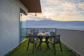 A balcony with a table and chairs, overlooking a mountainous landscape. - Alaya Stays BYDM The Sky Heaven - 4 BHK Penthouse 15 Min from Triveni Ghat With Balcony & Lift (Rishikesh)
