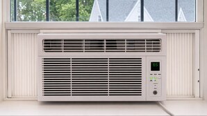 A window-mounted air conditioner with a digital display, set against a white wall with a window above it. - Studio Downtown+HighFalls+Kitchen+TV+Unity_Pet. (Rochester)