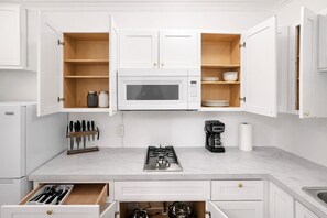 A kitchen with white cabinets, a microwave, a gas stove, a coffee maker, and a knife block. - Your Cozy Studio HighFalls TV Kitchen Rochest DT (Rochester)