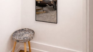 A room with a large mirror, a chair, a small round table, and a door. - Your Cozy Studio HighFalls TV Kitchen Rochest DT (Rochester)