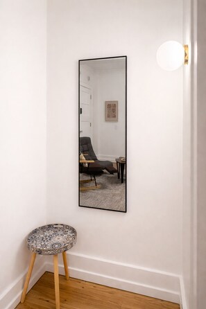 A room with a large mirror, a chair, a small round table, and a door. - Your Cozy Studio HighFalls TV Kitchen Rochest DT (Rochester)