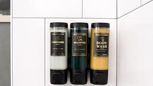 Three toiletry bottles on a tiled wall. - Your Cozy Studio HighFalls TV Kitchen Rochest DT (Rochester)