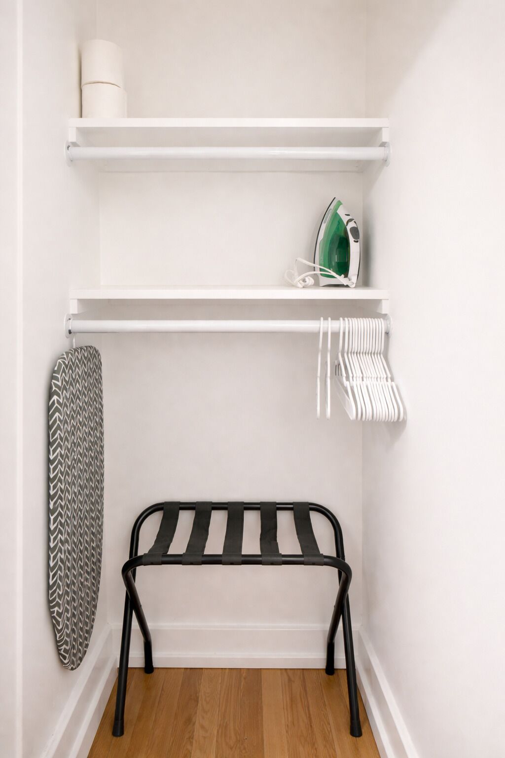 A small, neatly organized closet with shelves, a bench, and hanging items.