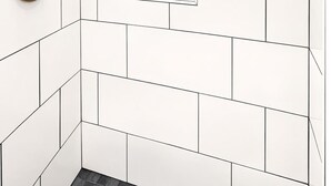 A bathroom with white tiled walls, a window, a showerhead, and a set of toiletries. - Your Cozy Studio HighFalls TV Kitchen Rochest DT (Rochester)