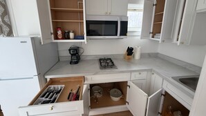 A compact kitchen with white cabinets, a microwave, a coffee maker, and a sink. - Modern studio in Downtown Rochester with a full kitchen and Smart TV, steps from High Falls. (Rochester)