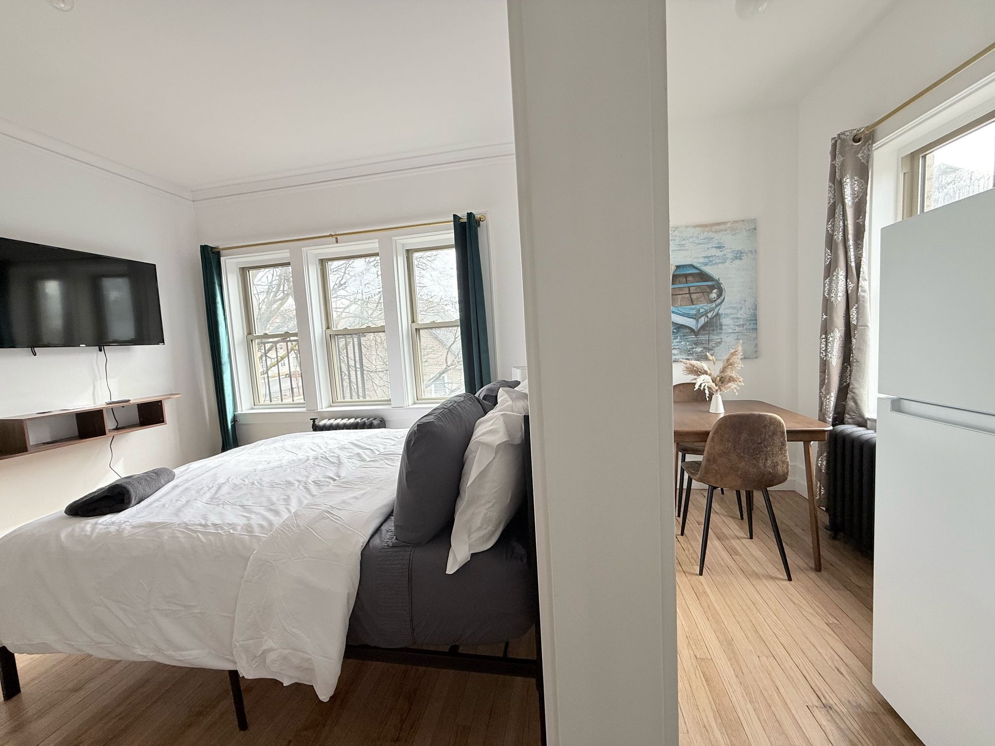 A modern bedroom with a bed, a desk, and a television.