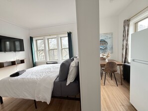 A modern bedroom with a bed, a desk, and a television. - Modern studio in Downtown Rochester with a full kitchen and Smart TV, steps from High Falls. (Rochester)