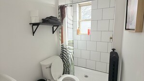 A modern bathroom with a toilet, shower, and sink. - Modern studio in Downtown Rochester with a full kitchen and Smart TV, steps from High Falls. (Rochester)