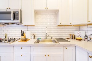 Een moderne keuken met witte kasten, een roestvrijstalen spoelbak en een magnetron.