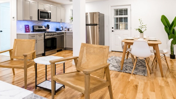 A modern kitchen with stainless steel appliances, a dining area with a table and chairs, and a large plant. - Cornhill1BED,Cozy,WiFi_EquipKitchen_TV+HighFalls (Rochester)