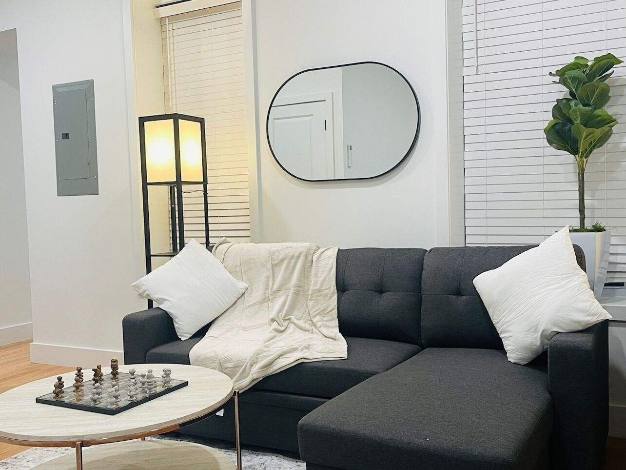 A modern living room with a dark grey sofa, a round coffee table, and a chessboard.