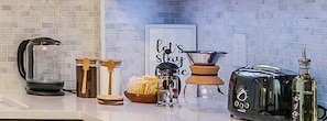 A kitchen counter with a coffee maker, a kettle, a toaster, a bottle, and a sign that says "let's stay." - Cornhil 1Bed-EquippedKitchen,HighFalls,DT,TV_WiFi (Rochester)