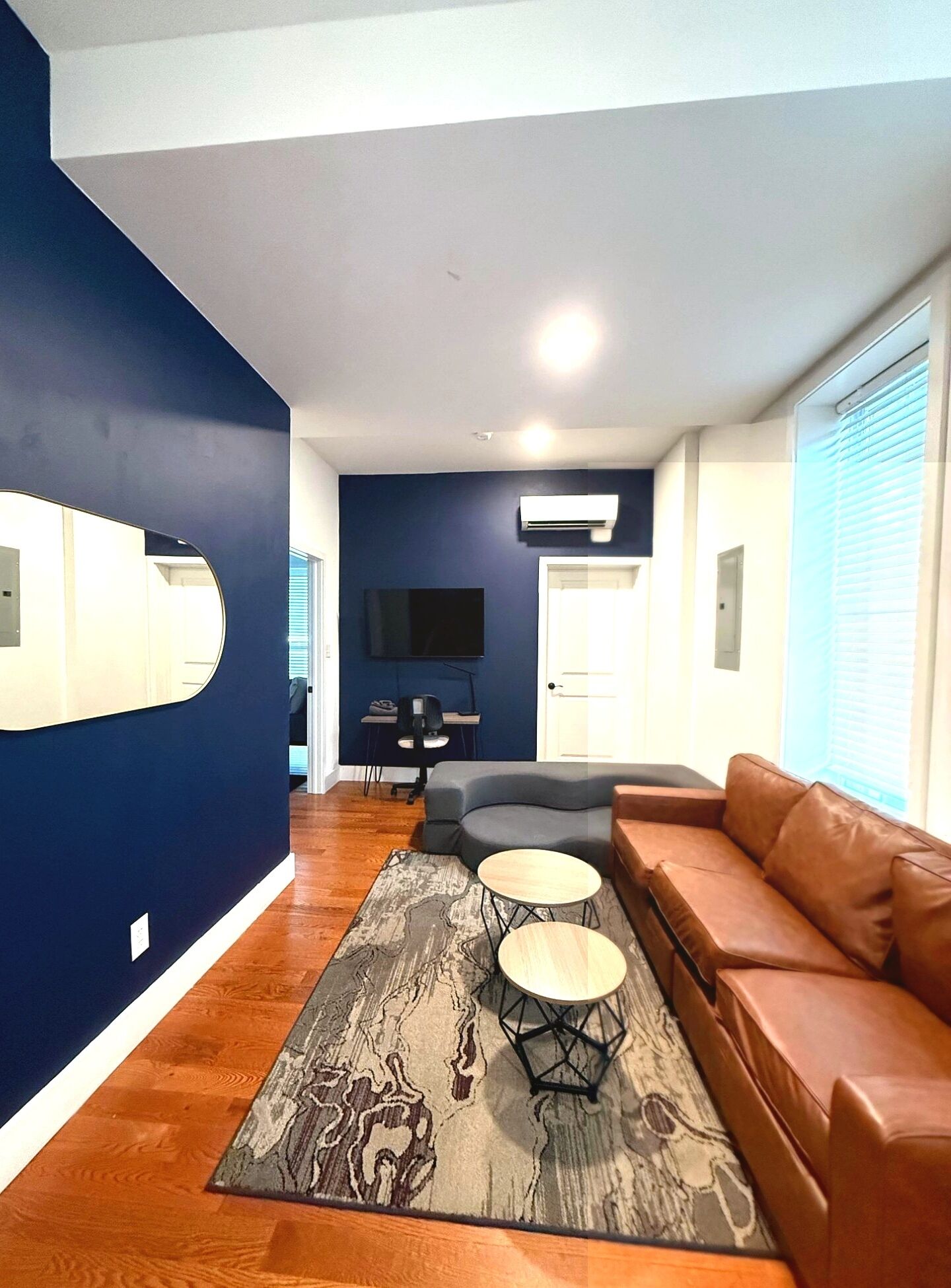 A living room with a brown leather sofa, a gray sectional, a coffee table, and a patterned rug.