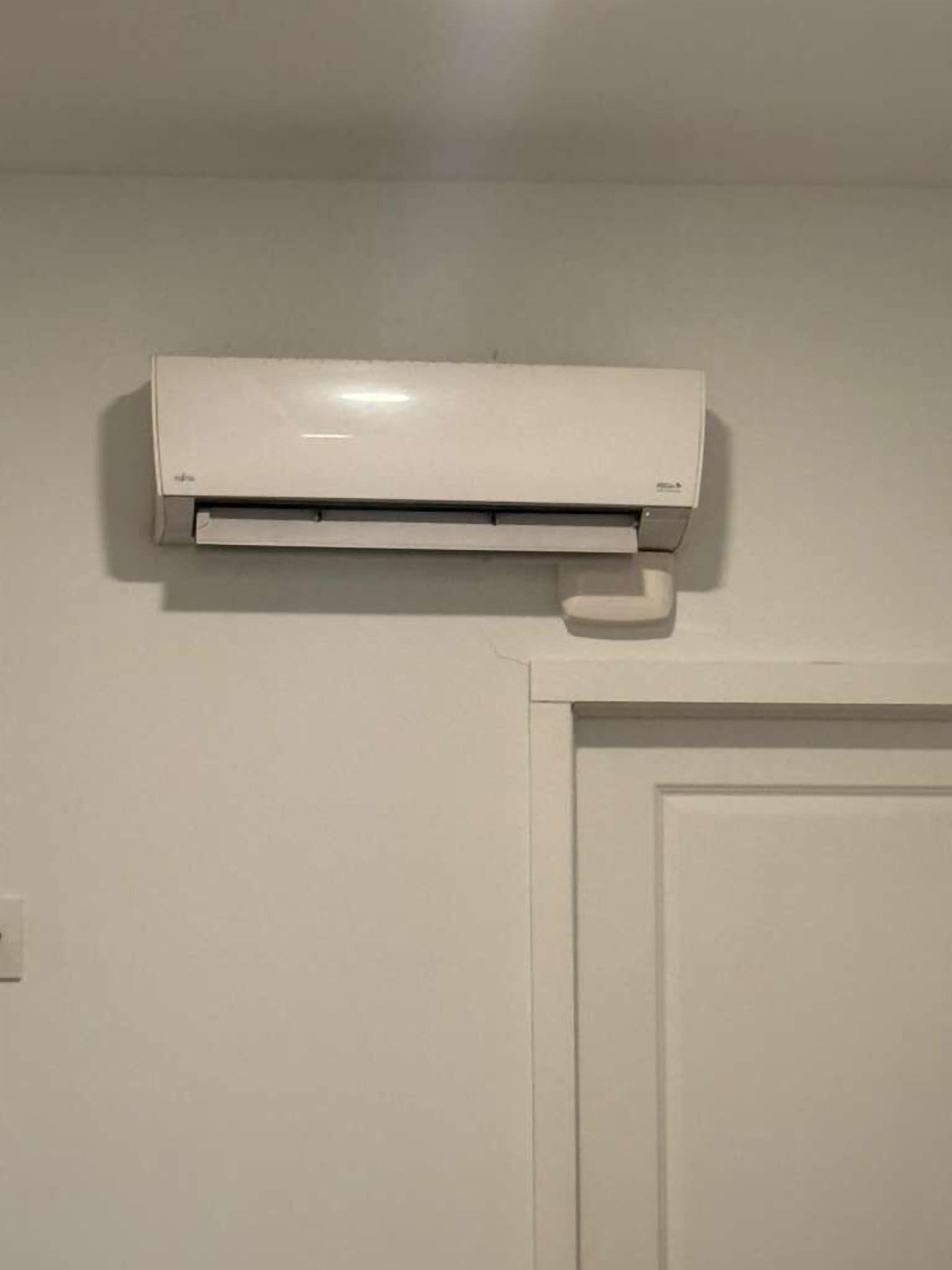 Eine weiße Klimaanlage ist an einer Wand oberhalb einer weißen Tür angebracht.