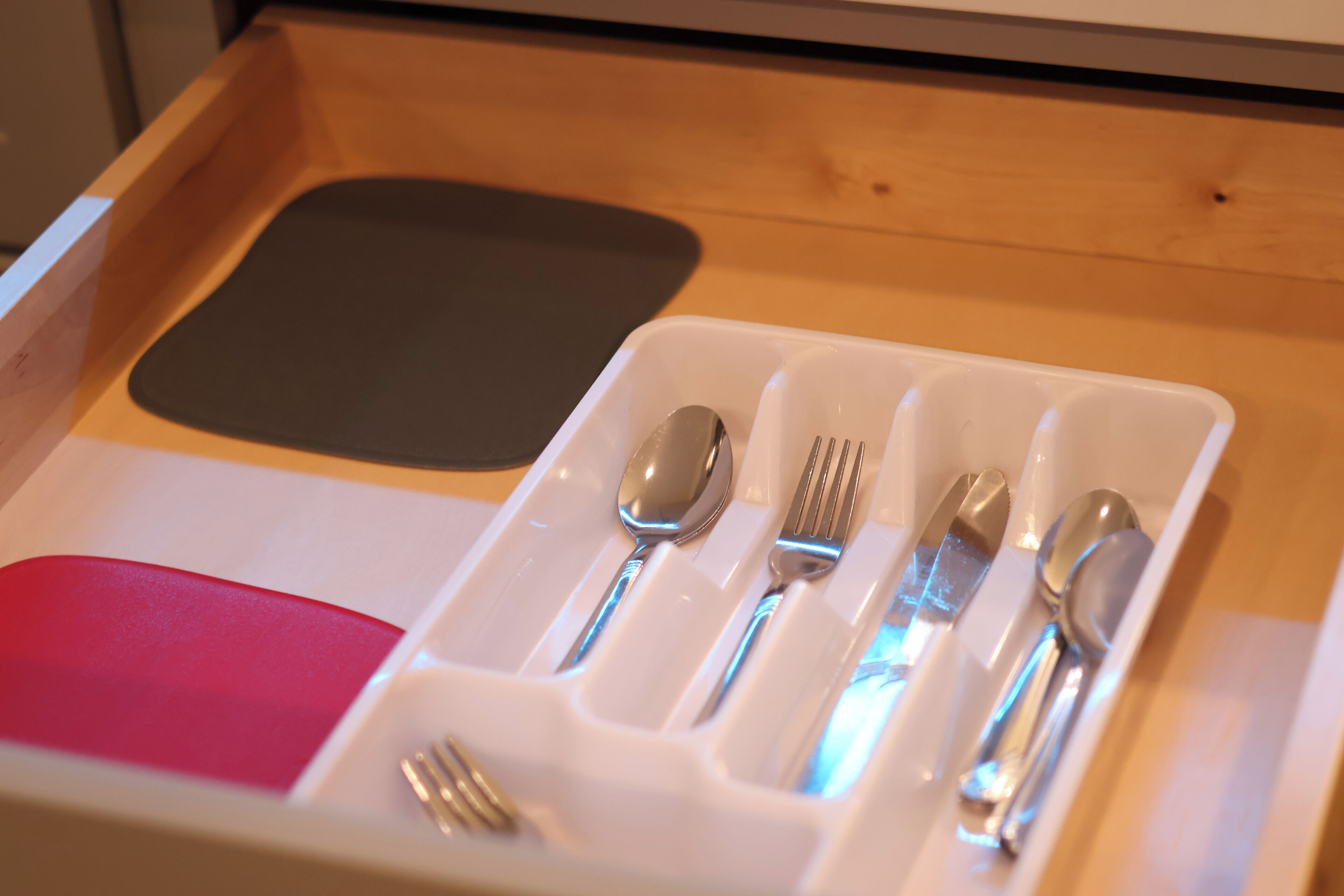 A drawer with a compartmentalized tray holding cutlery and a napkin.