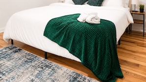 A bedroom with a white bed, green throw blanket, and matching pillows. - Cozy 1BR with equipped kitchen, dining table, TV, Wi-Fi, near High Falls (Rochester)