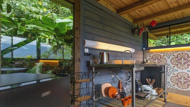 A modern kitchen with a large window, a sink, and various kitchen utensils. - Chalé em Garuva com Vista para a Montanha (Garuva)