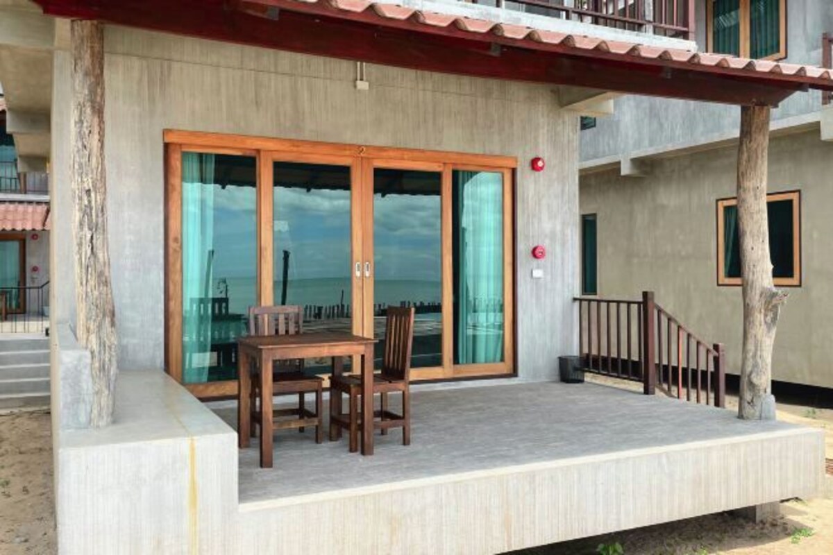 A beachfront property with a covered patio, a dining table, and a view of the ocean.