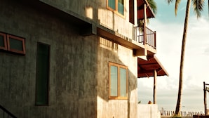 A two-story building with a balcony, a staircase, and a sandy ground. - Laemsui Beach (Chaiya)
