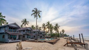 A beachfront hotel with multiple buildings, a swimming pool, and palm trees. - Laemsui Beach (Chaiya)