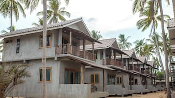 A row of concrete buildings with balconies, surrounded by palm trees.