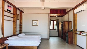 A bedroom with two beds, wooden furniture, a wardrobe, and a small kitchenette. - Laemsui Beach (Chaiya)