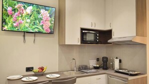 A modern kitchen with a flat-screen TV, a microwave, and a coffee maker. - Amara Porto Living | Apartment 1 (Chania)