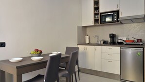 A modern kitchen with a dining table, chairs, a microwave, a coffee maker, and a dishwasher. - Amara Porto Living | Apartment 2 (Chania)