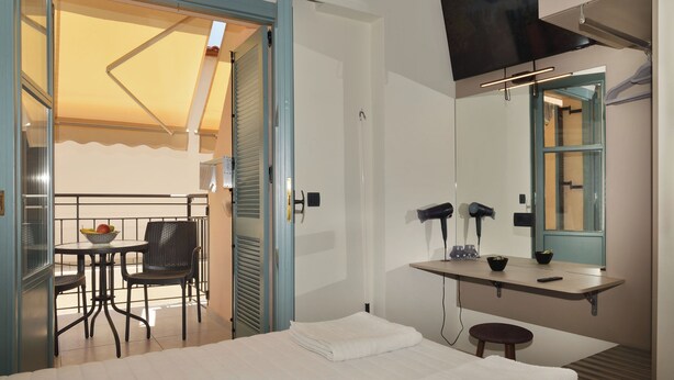 A hotel room with a bed, a desk with a mirror, a hairdryer, and a chair. - Amara Porto Living | Apartment 2 (Chania)